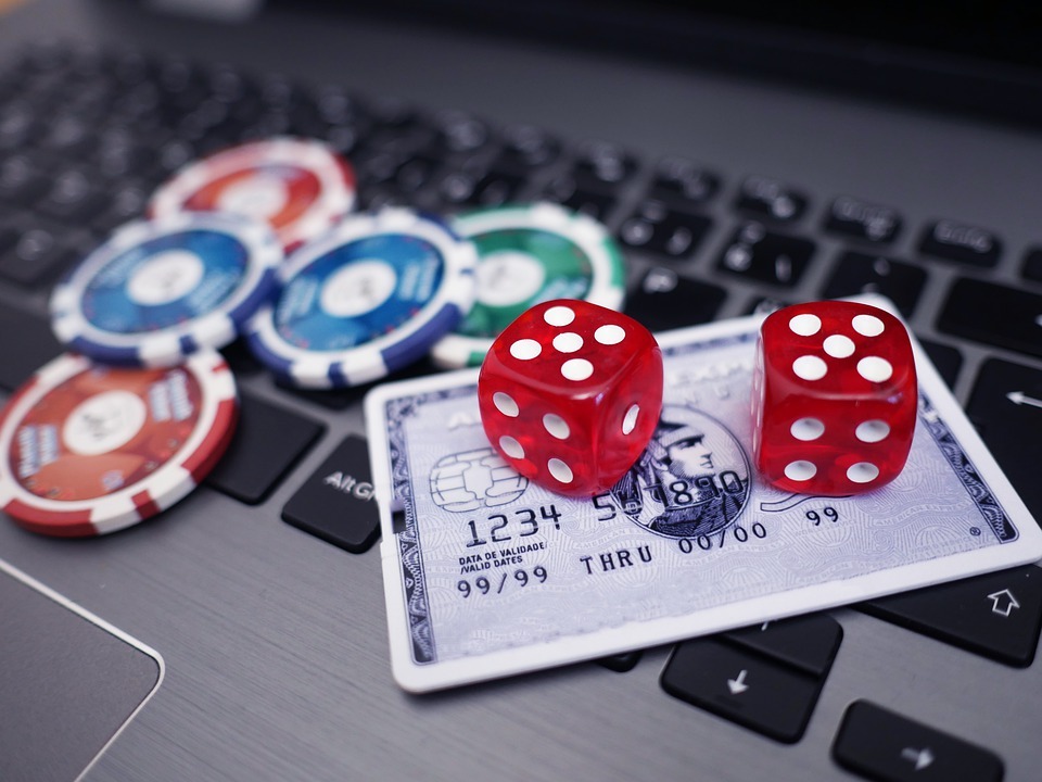 credit card on laptop keyboard with dice and poker chips
